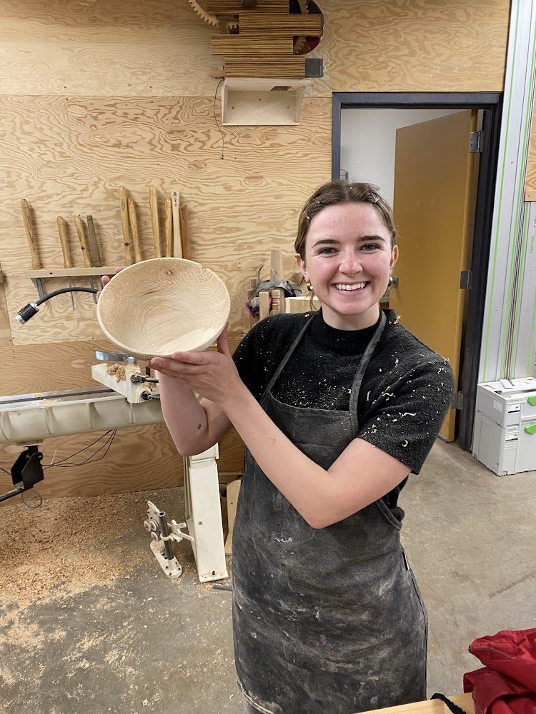 A guild member holding a hand-turned wooden bowl